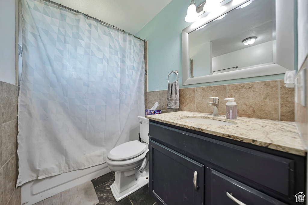 Bathroom with tile walls, vanity, shower / tub combo with curtain, tile patterned floors, and wainscoting