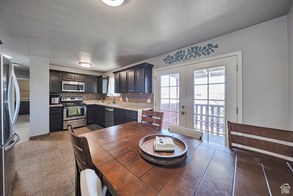 Kitchen with stainless steel appliances, french doors, decorative backsplash, a textured ceiling, and light tile patterned floors