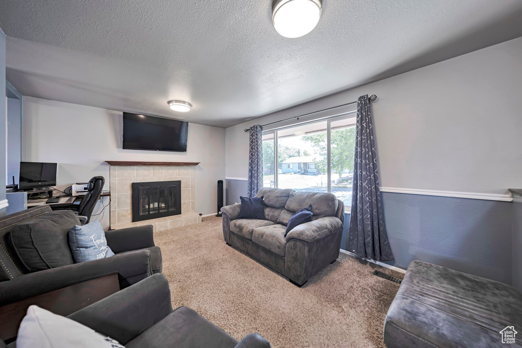 Carpeted living room with a textured ceiling and a fireplace