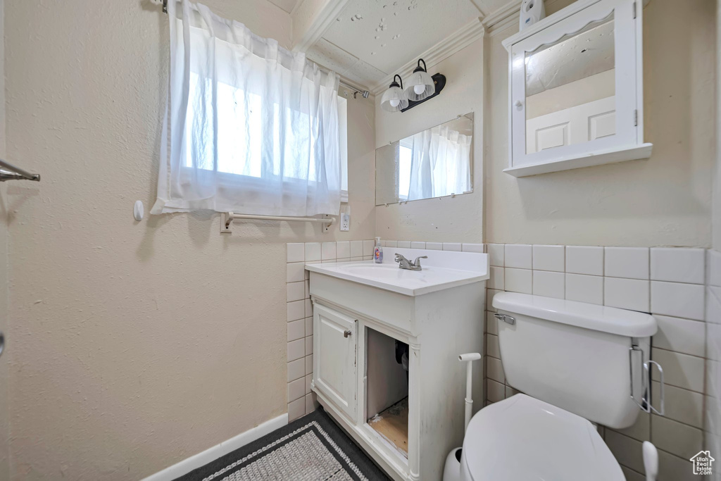 Half bathroom with vanity, tile walls, and a wainscoted wall