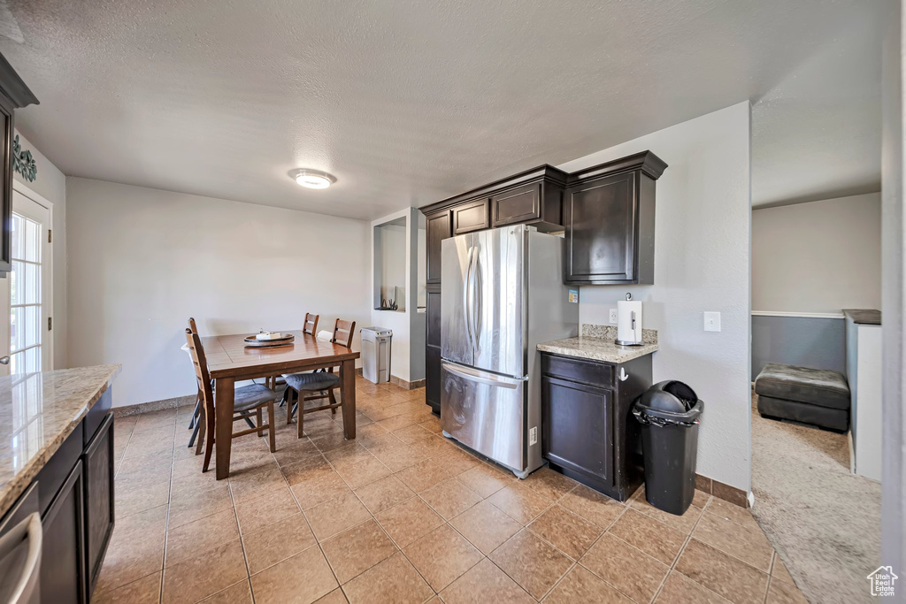 Kitchen featuring stainless steel appliances, light stone counters, a textured ceiling, and dark brown cabinets