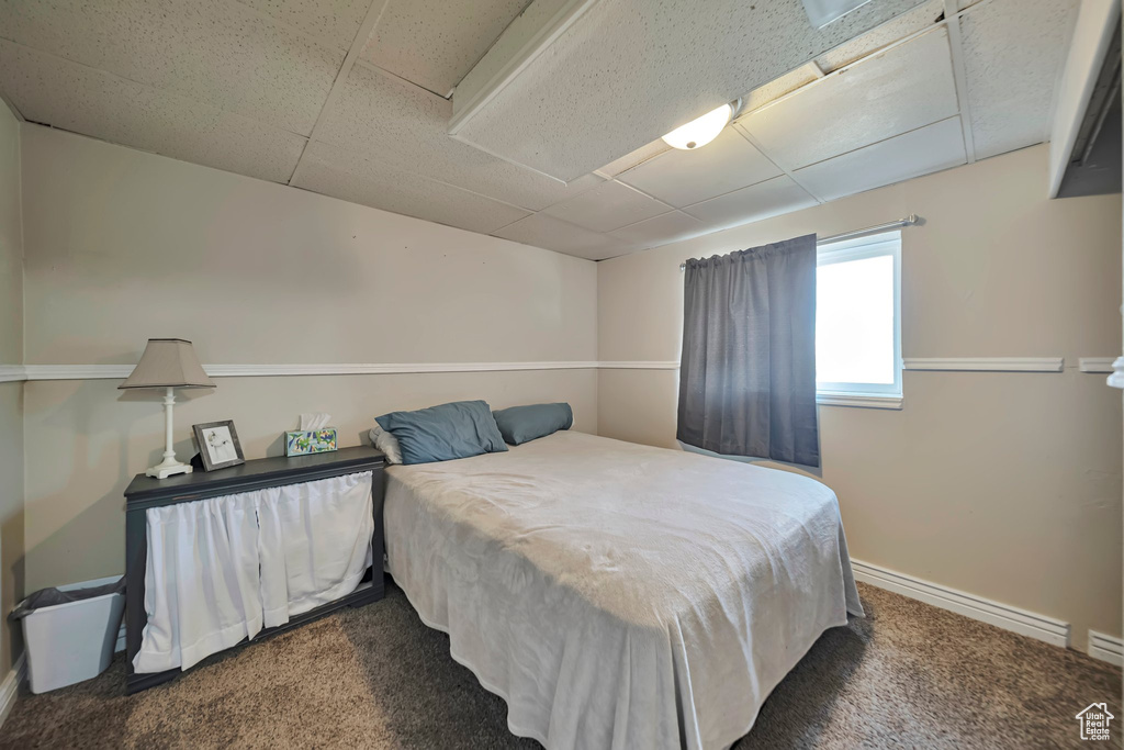 Carpeted bedroom featuring baseboards and a drop ceiling