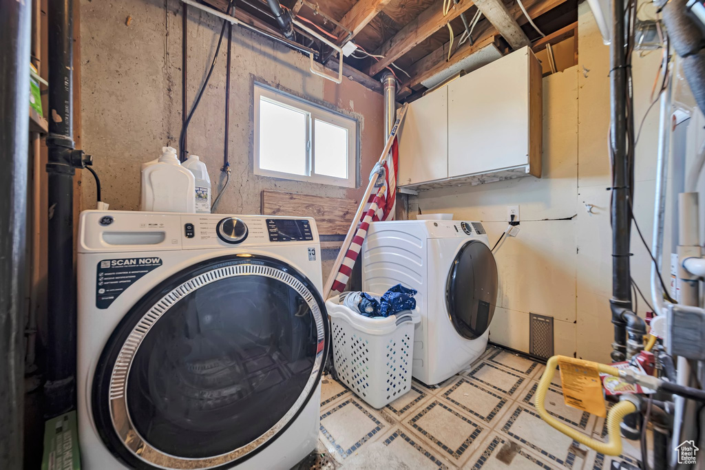 Washroom with cabinet space, independent washer and dryer, and light flooring
