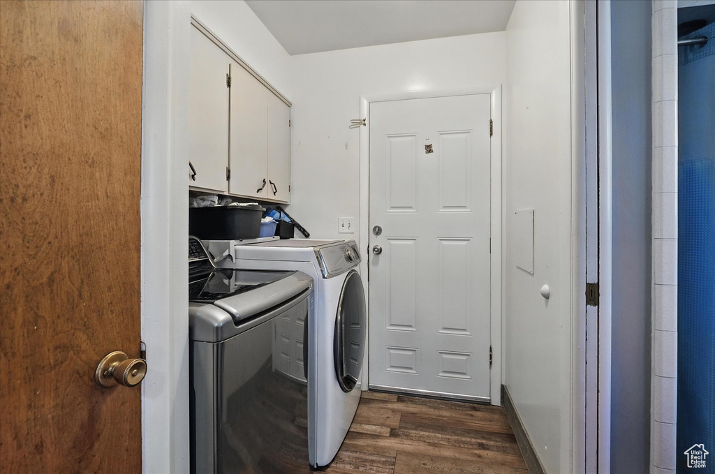 Laundry area with cabinet space, washer and dryer, and dark wood-type flooring