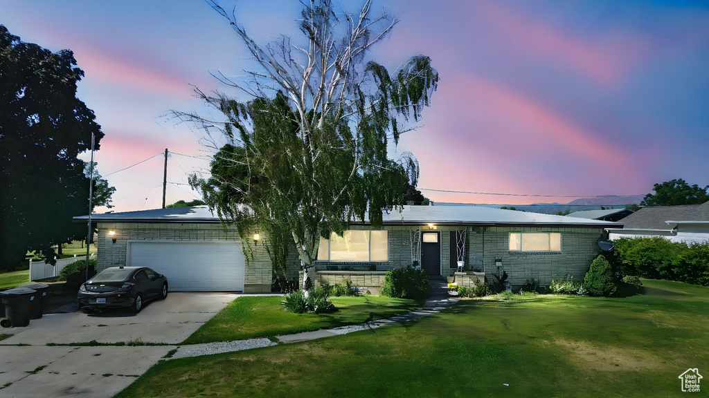 Ranch-style house with brick siding, an attached garage, concrete driveway, and a front lawn