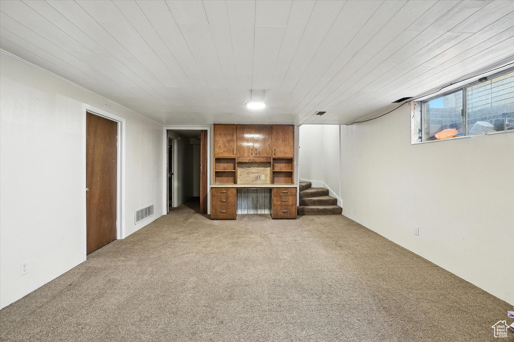 Unfurnished living room featuring light colored carpet and stairs