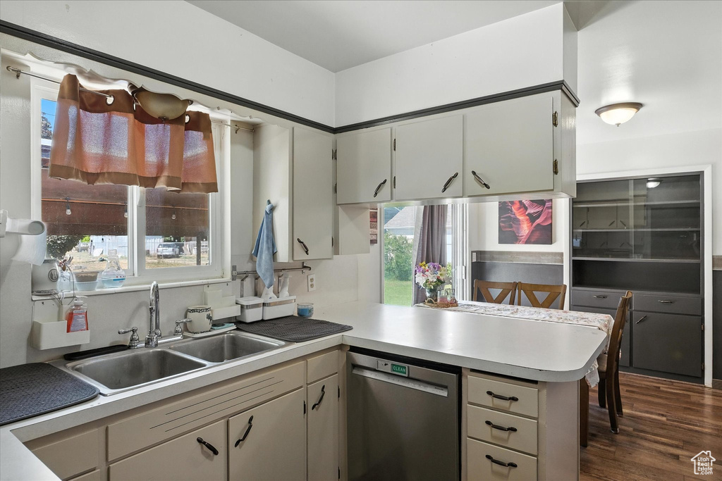 Kitchen featuring dishwasher, a peninsula, light countertops, and dark wood-style flooring