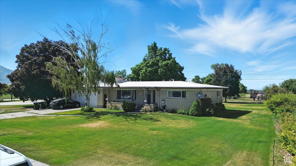 View of front of home featuring driveway, a front lawn, and brick siding