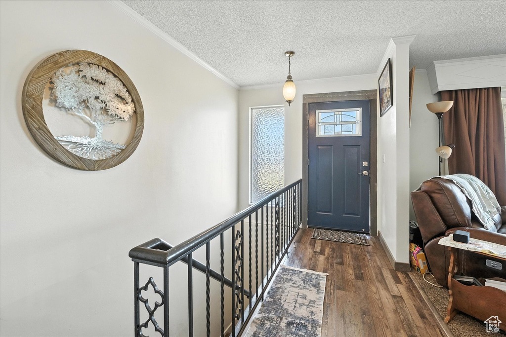 Foyer entrance featuring hardwood / wood-style flooring, a textured ceiling, and crown molding
