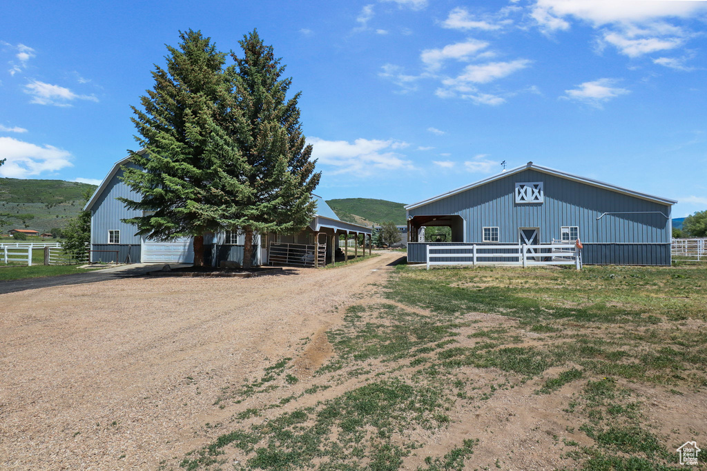 View of side of home with dirt driveway, an outbuilding, and an exterior structure