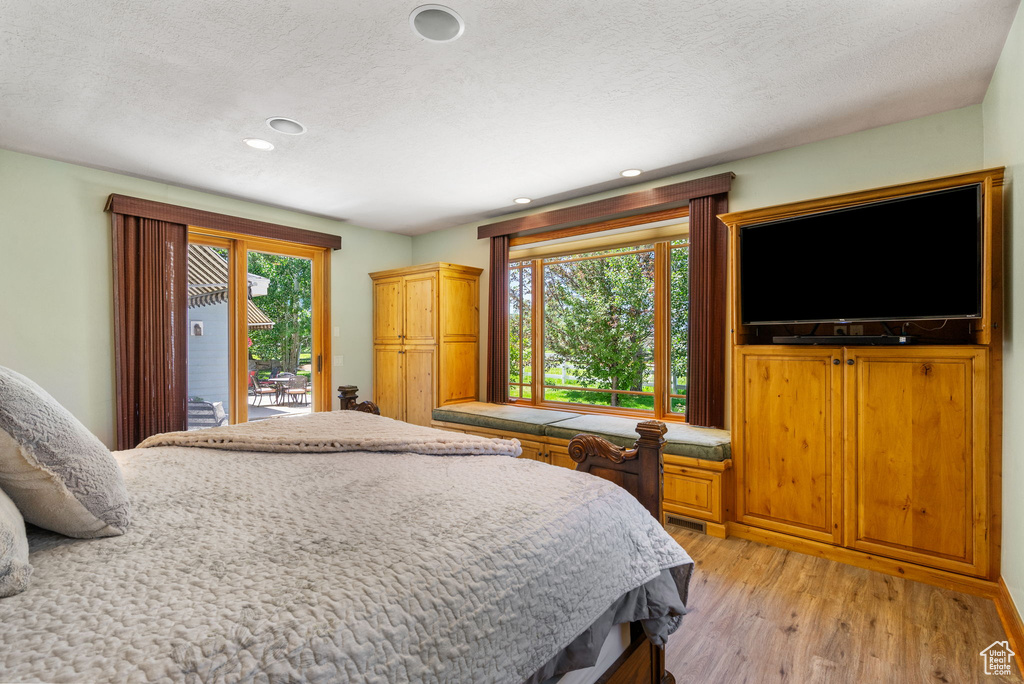 Bedroom with access to exterior, light wood-style flooring, recessed lighting, and a textured ceiling