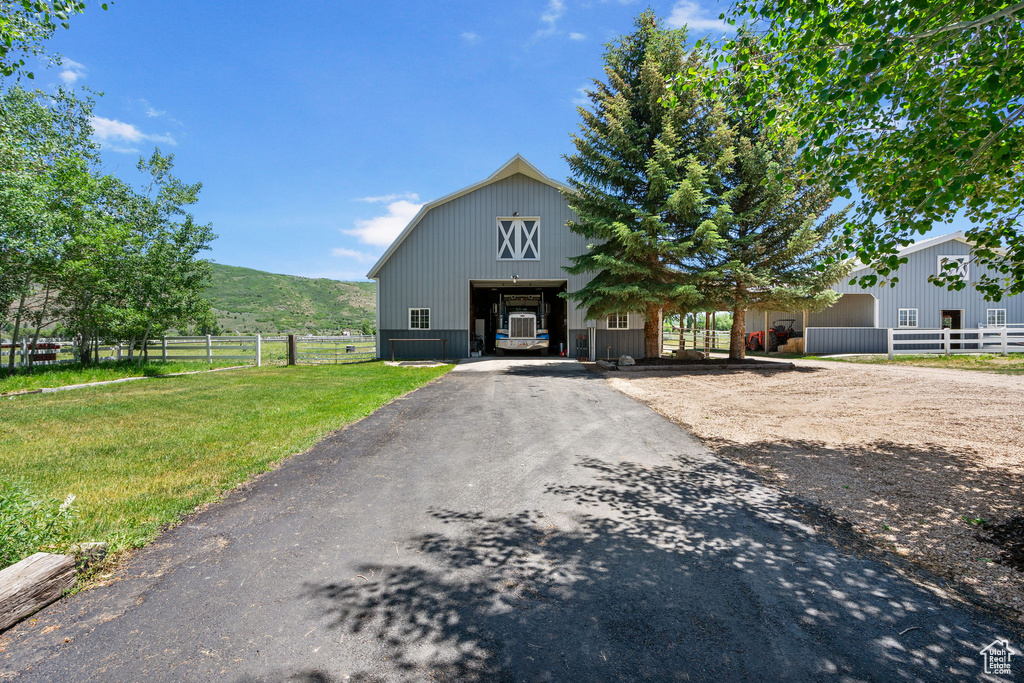 View of front of home featuring driveway, an outbuilding, a detached garage, and a barn