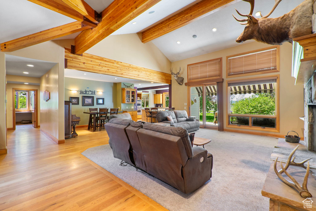 Living room featuring recessed lighting, beam ceiling, high vaulted ceiling, and light wood-style floors