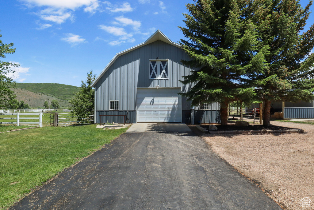 View of front facade with a barn, a detached garage, an outdoor structure, asphalt driveway, and a mountain view