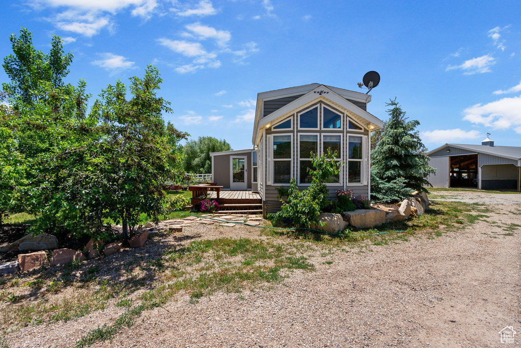 Back of house with a deck, dirt driveway, and a carport