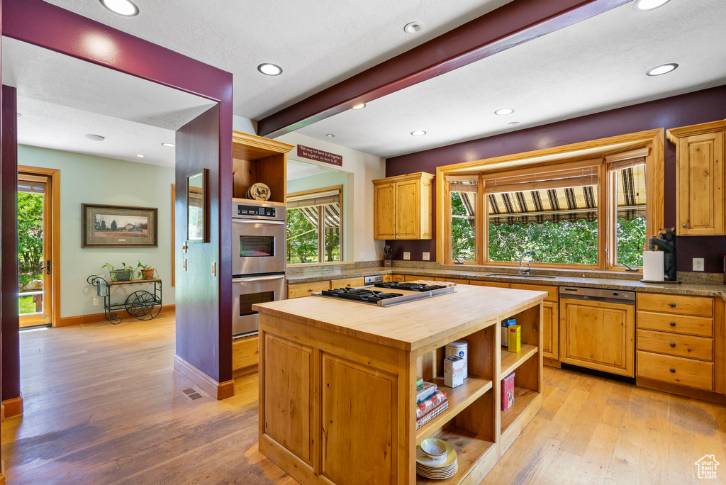 Kitchen with open shelves, stainless steel appliances, butcher block countertops, light wood-type flooring, and plenty of natural light