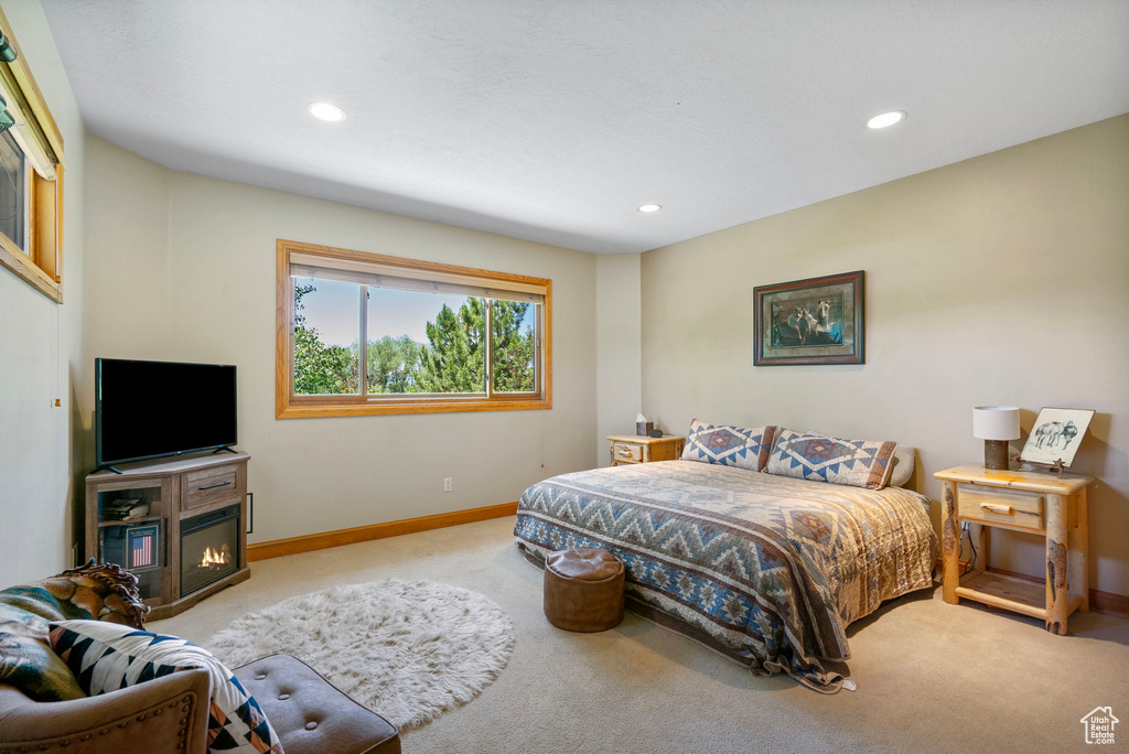 Bedroom with carpet, a glass covered fireplace, and recessed lighting