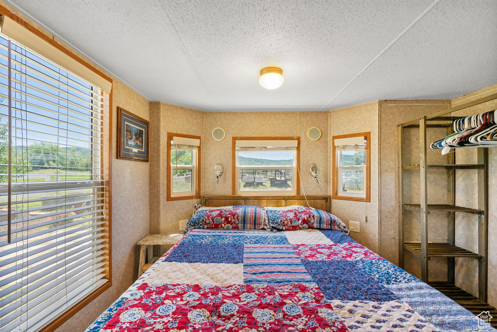 Bedroom featuring a textured ceiling and wallpapered walls
