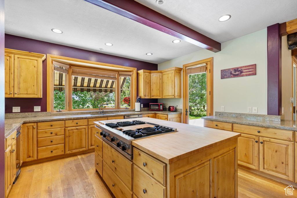 Kitchen featuring stainless steel gas cooktop, butcher block countertops, light wood finished floors, a center island, and beamed ceiling