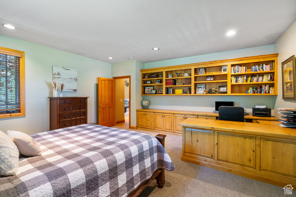 Bedroom with built in desk, recessed lighting, and light colored carpet