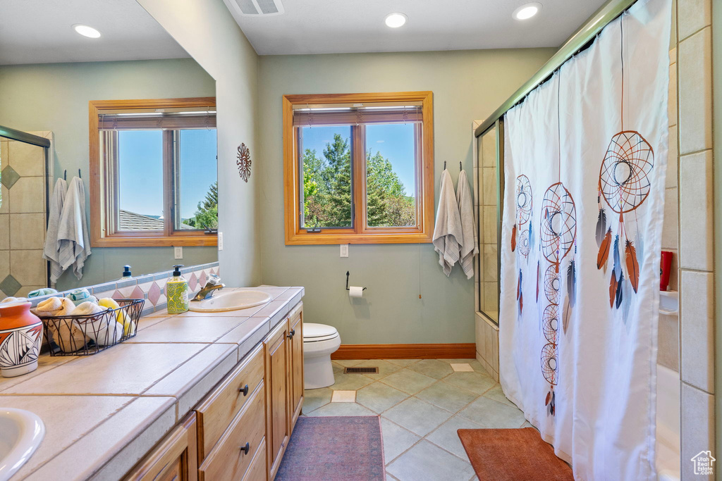 Bathroom with healthy amount of natural light, double vanity, tile patterned floors, recessed lighting, and shower / bathtub combination with curtain