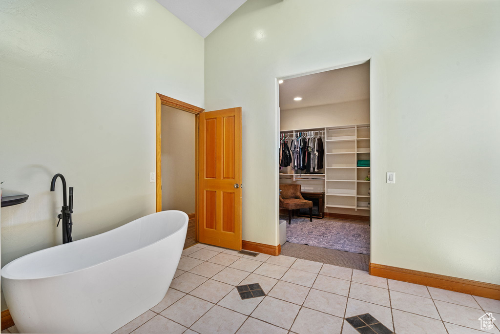 Full bathroom featuring a freestanding tub, tile patterned flooring, a spacious closet, high vaulted ceiling, and recessed lighting