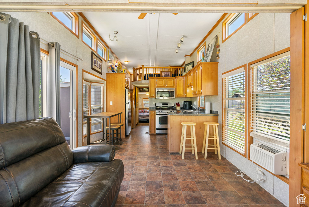 Kitchen with stainless steel appliances, open floor plan, a ceiling fan, dark stone finish flooring, and a peninsula