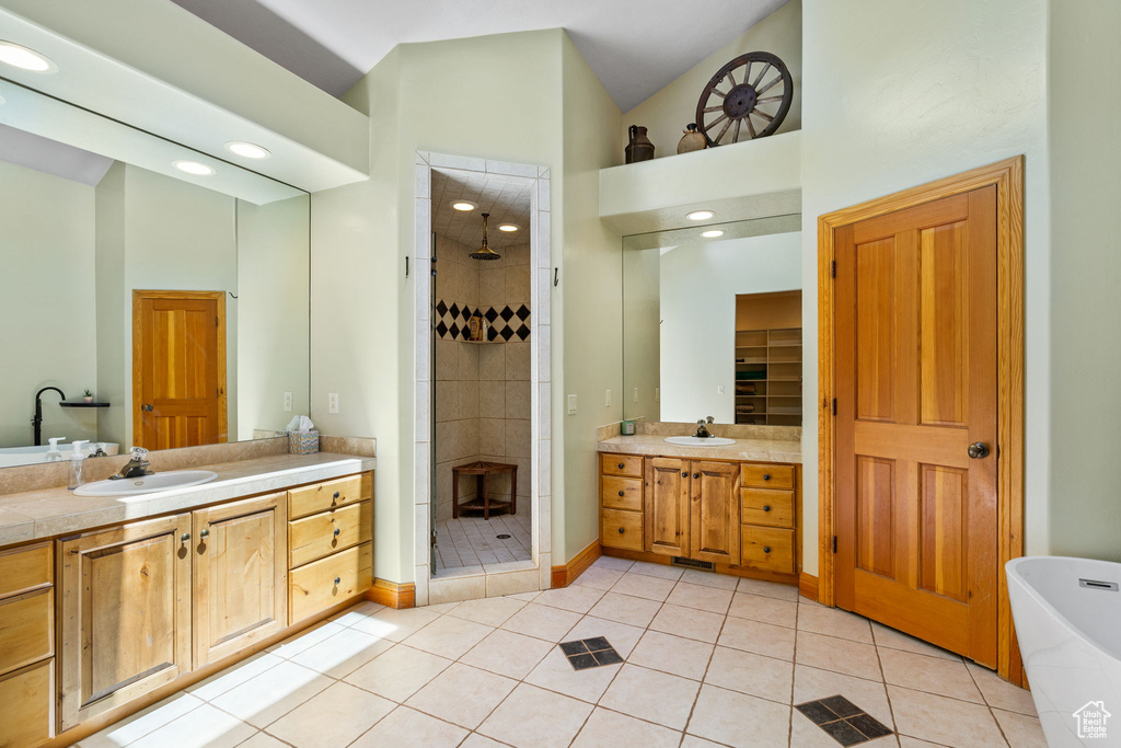 Full bath with a shower stall, two vanities, tile patterned floors, a freestanding tub, and high vaulted ceiling