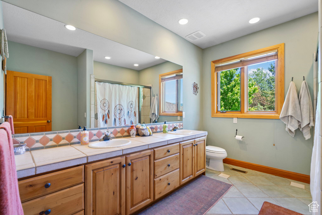 Full bath with a shower with shower curtain, double vanity, tile patterned floors, and recessed lighting