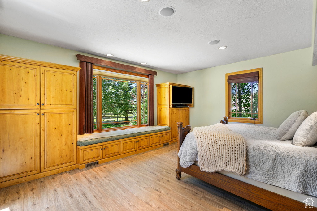Bedroom with multiple windows, light wood-type flooring, and recessed lighting