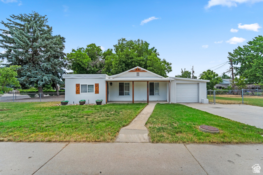 View of front of home with a garage, a porch, driveway, and stucco siding
