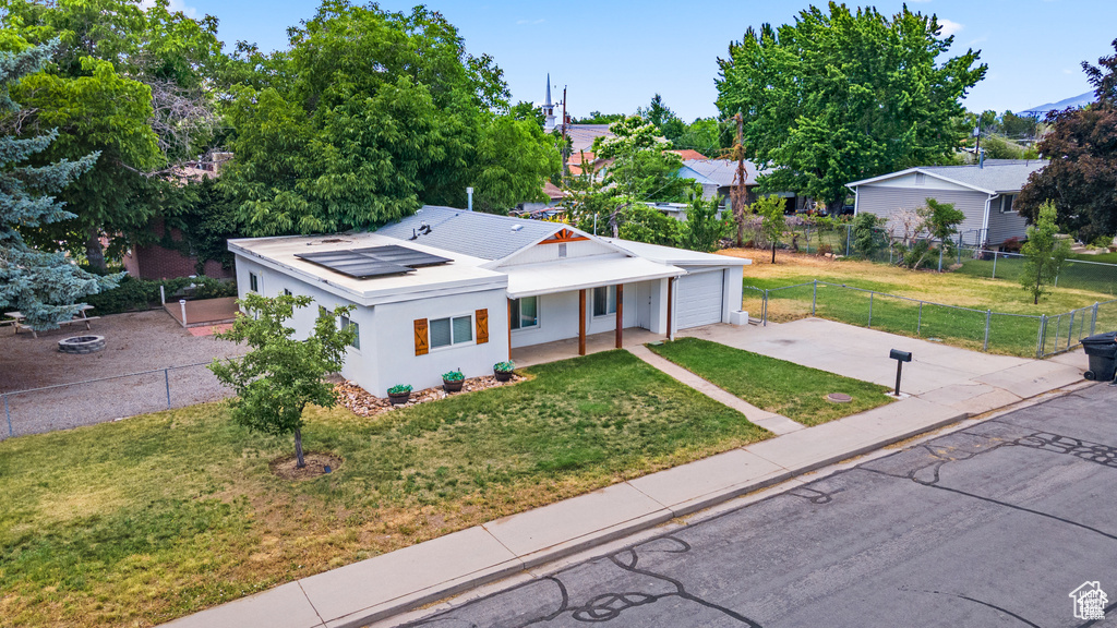 View of front of home featuring roof mounted solar panels, driveway, stucco siding, and a porch
