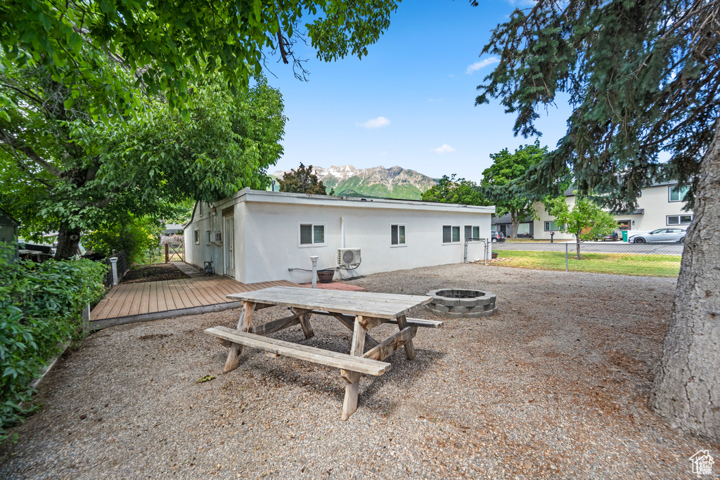 Back of property featuring a fire pit, a deck with mountain view, and stucco siding