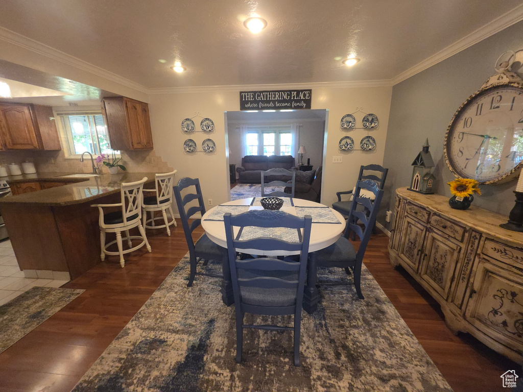 Dining space featuring dark wood finished floors, ornamental molding, and recessed lighting