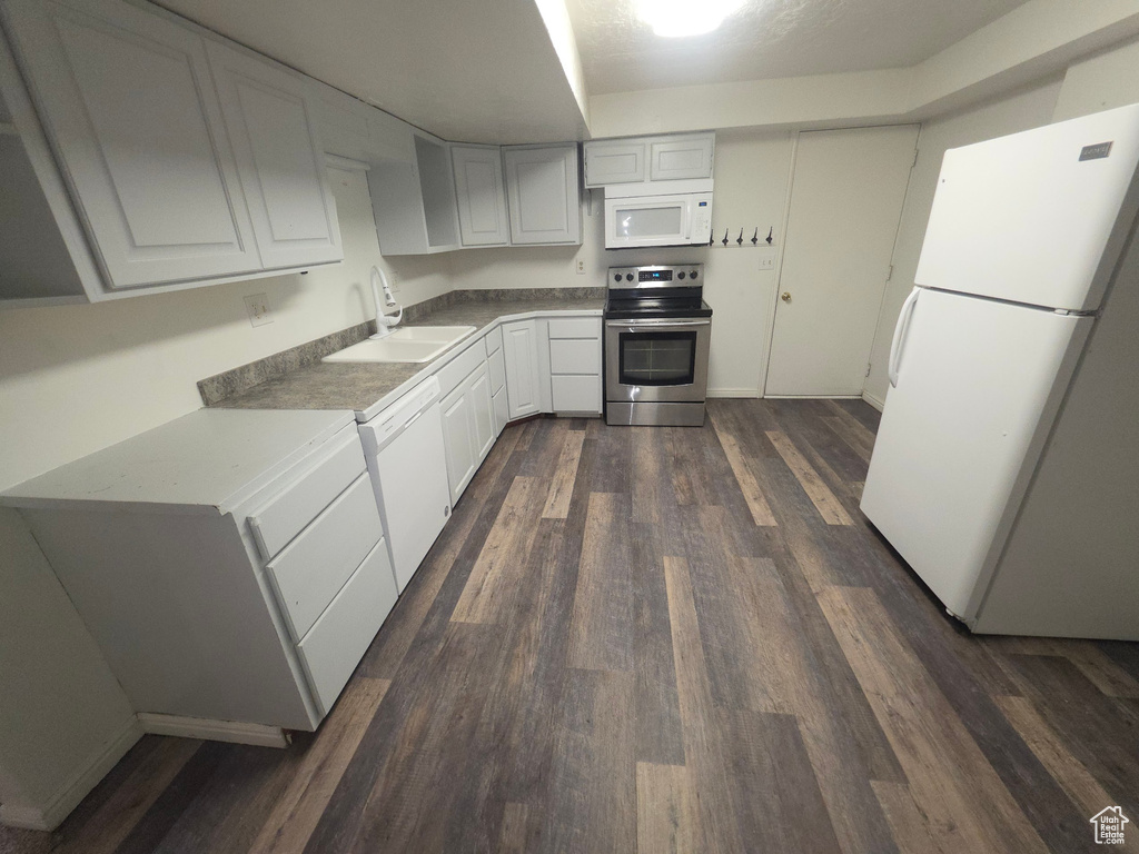Kitchen featuring white appliances, dark wood-style flooring, and white cabinetry