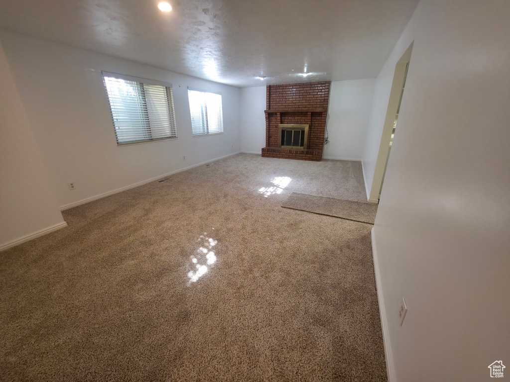 Unfurnished living room featuring carpet and a fireplace