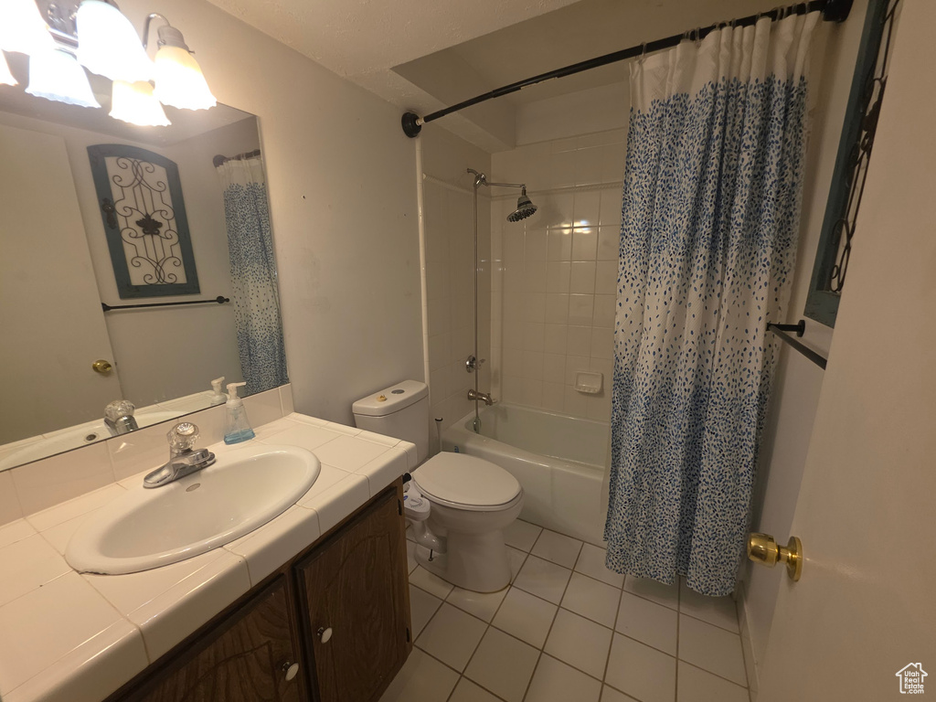 Bathroom featuring tile patterned flooring, vanity, shower / bath combo with shower curtain, and a chandelier