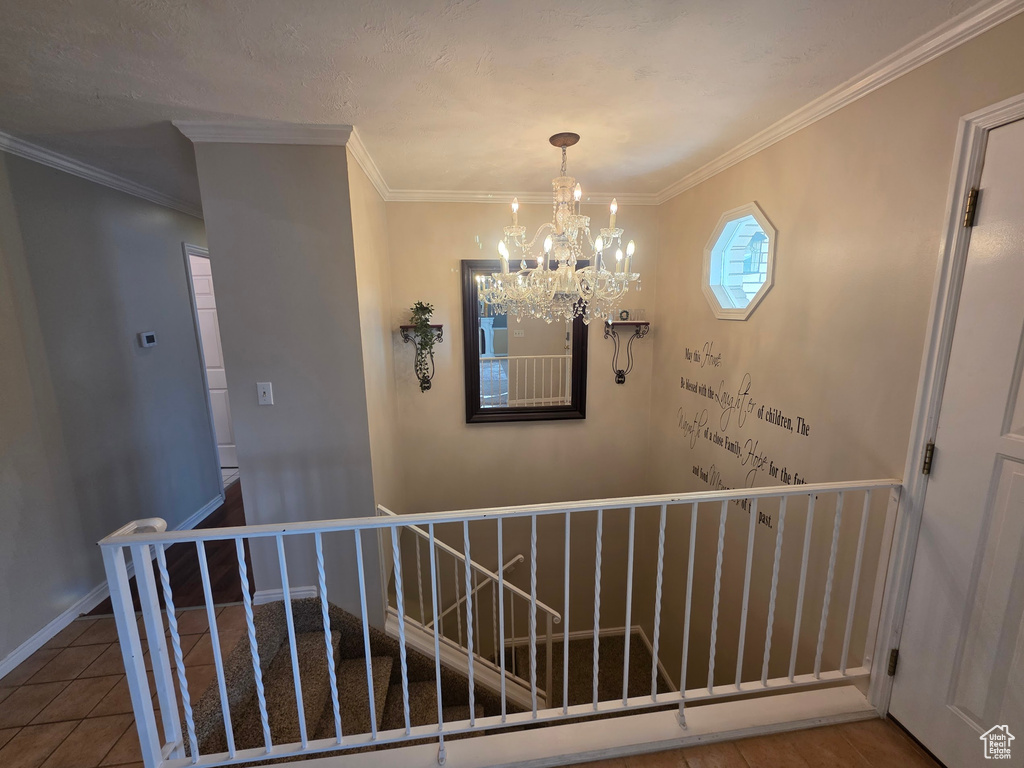 Staircase featuring a chandelier, ornamental molding, and tile patterned floors