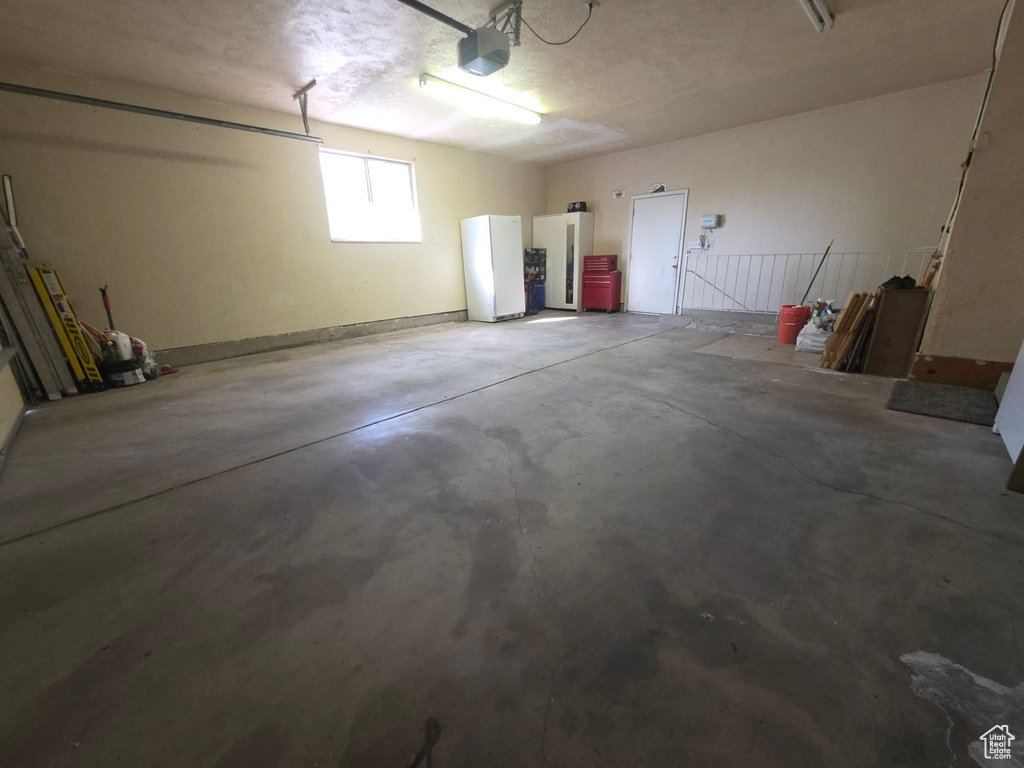 Garage with a garage door opener and freestanding refrigerator