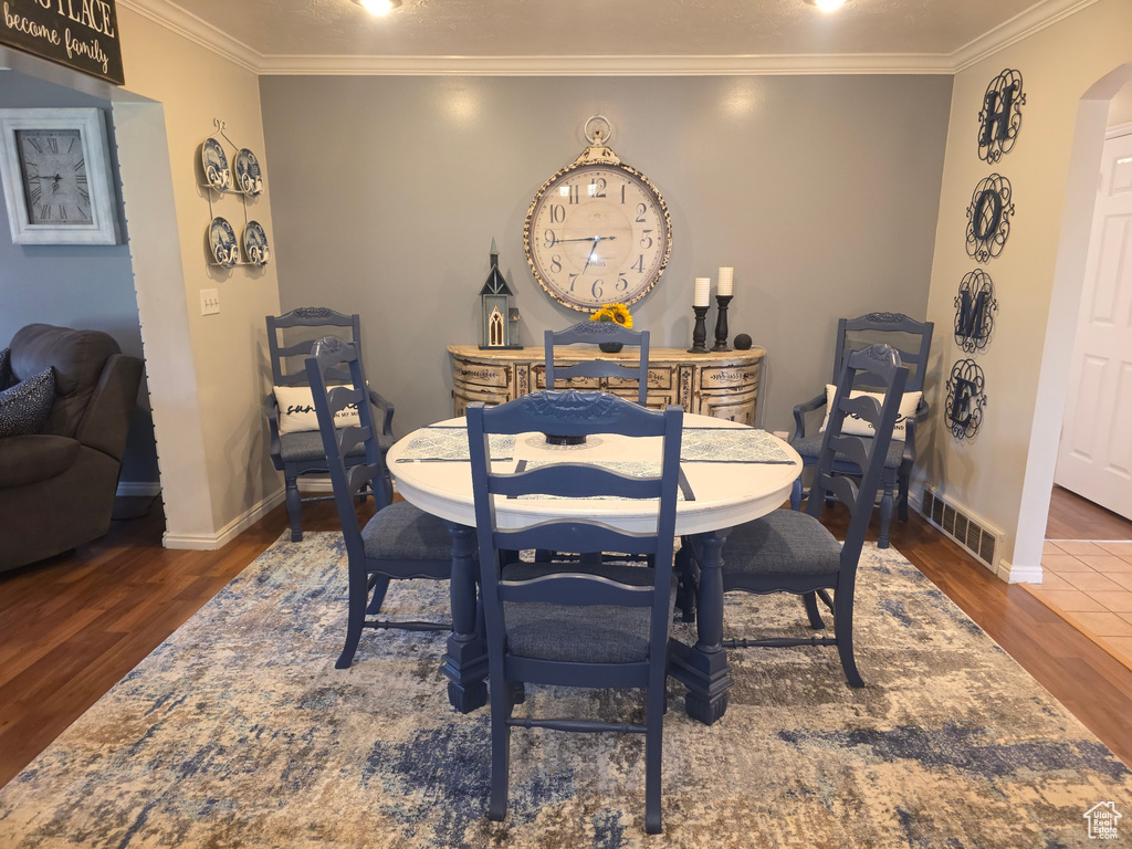 Dining area featuring wood finished floors, ornamental molding, and arched walkways