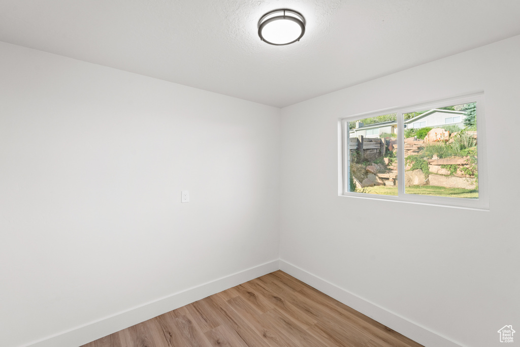Empty room featuring baseboards and light wood-type flooring
