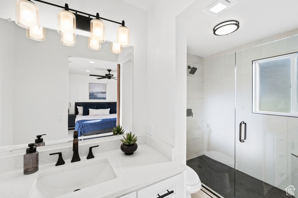 Ensuite bathroom featuring a shower stall, vanity, and ceiling fan