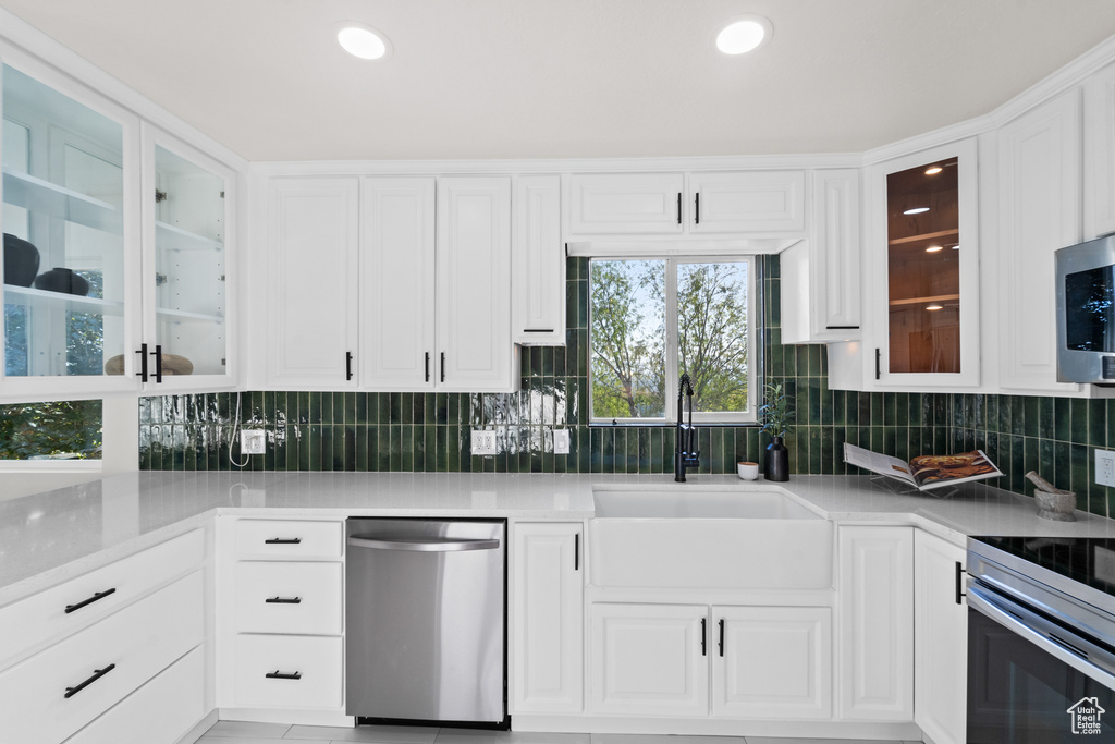 Kitchen featuring stainless steel appliances, tasteful backsplash, white cabinets, light countertops, and recessed lighting