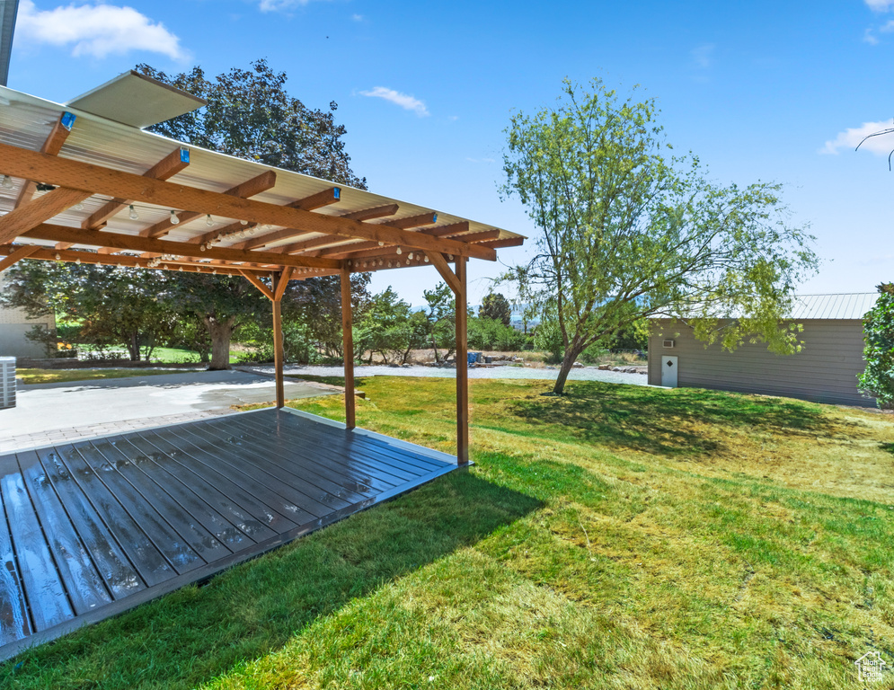 View of grassy yard featuring a pergola and a patio area