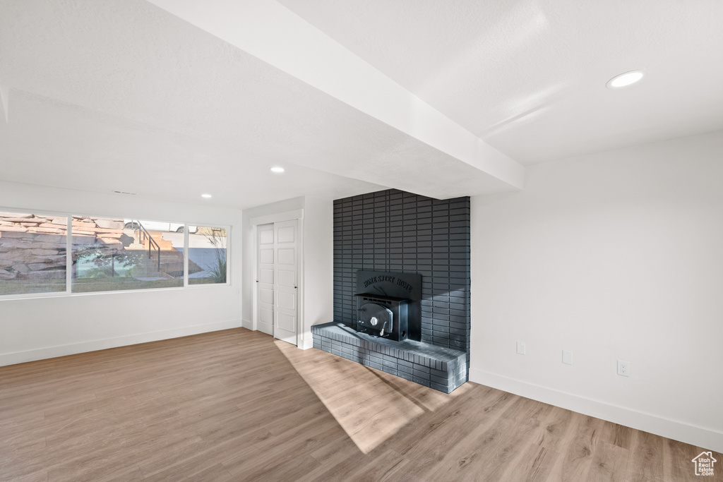 Unfurnished living room with wood finished floors, recessed lighting, and a large fireplace