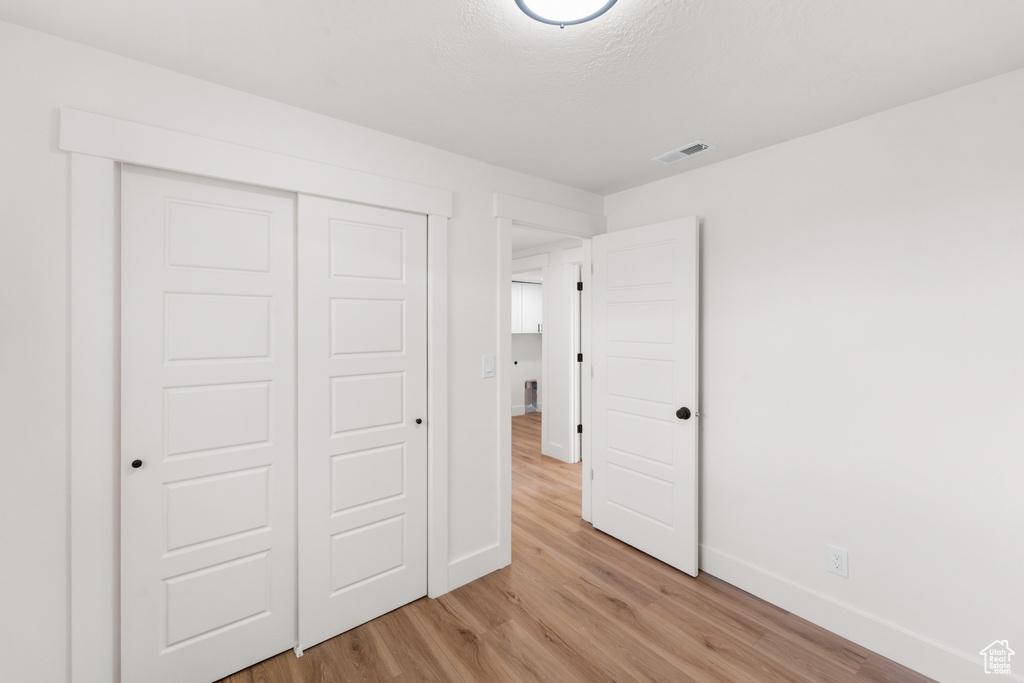 Unfurnished bedroom featuring light wood-type flooring and a closet