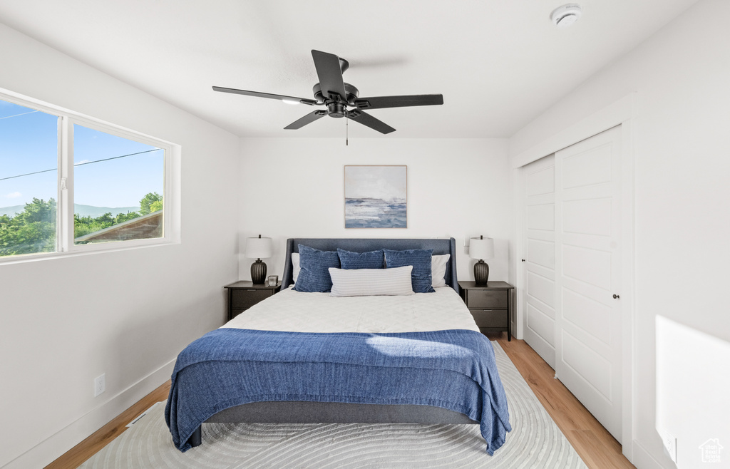 Bedroom with light wood-style flooring, a closet, and ceiling fan