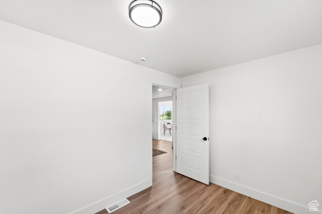 Empty room featuring light wood-style flooring and a smoke detector