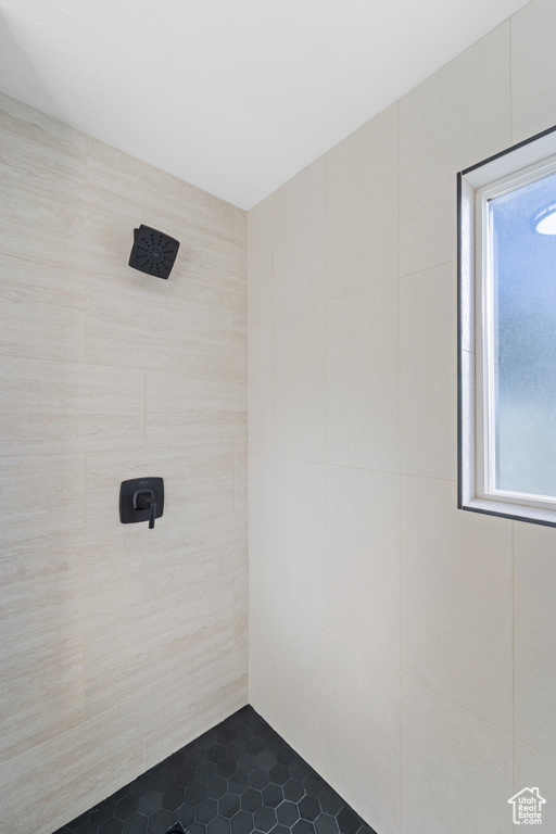 Bathroom with a tile shower, plenty of natural light, tile patterned flooring, and tile walls