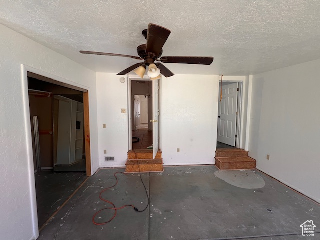 Unfurnished bedroom featuring a textured ceiling, concrete flooring, and ceiling fan